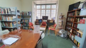 A picture of a library with library shelves against the walls and a large desk in the foreground